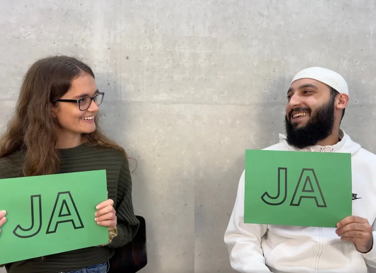 Zwei Personen halten grüne Schilder mit der Aufschrift JA hoch